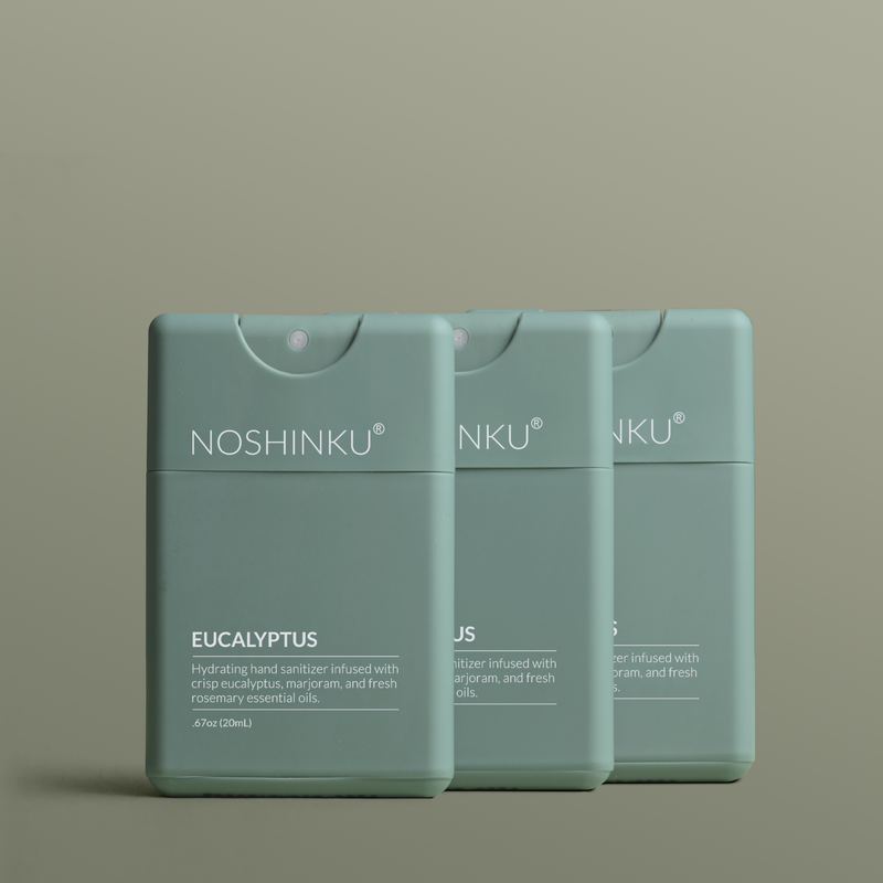 Three green Noshinku refillable Eucalyptus Hydrating Pocket hand sanitizer sprayers on a green background