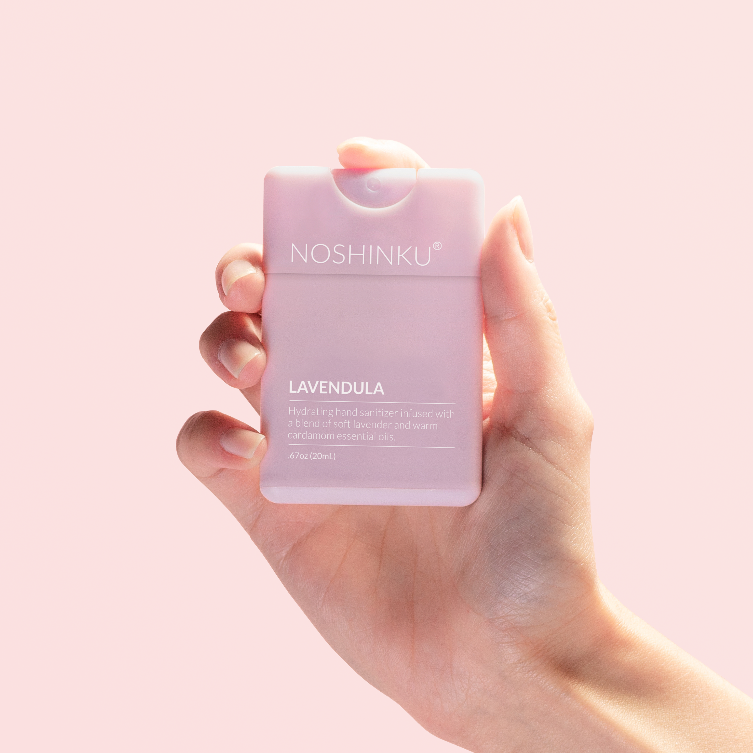 Noshinku Lavender Hydrating Pocket Spray Hand Sanitizer In Hand on pink background